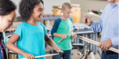 kids smiling at a teacher while playing the drums