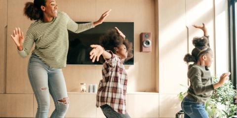 a mother and her two daughters dancing in the living room